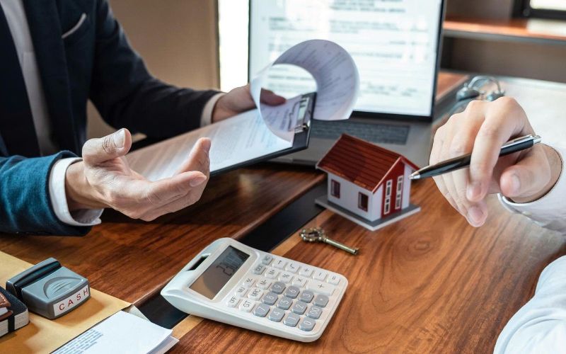 Nhân viên tư vấn bất động sản trao đổi thông tin và tính toán chi phí giao dịch nhà đất